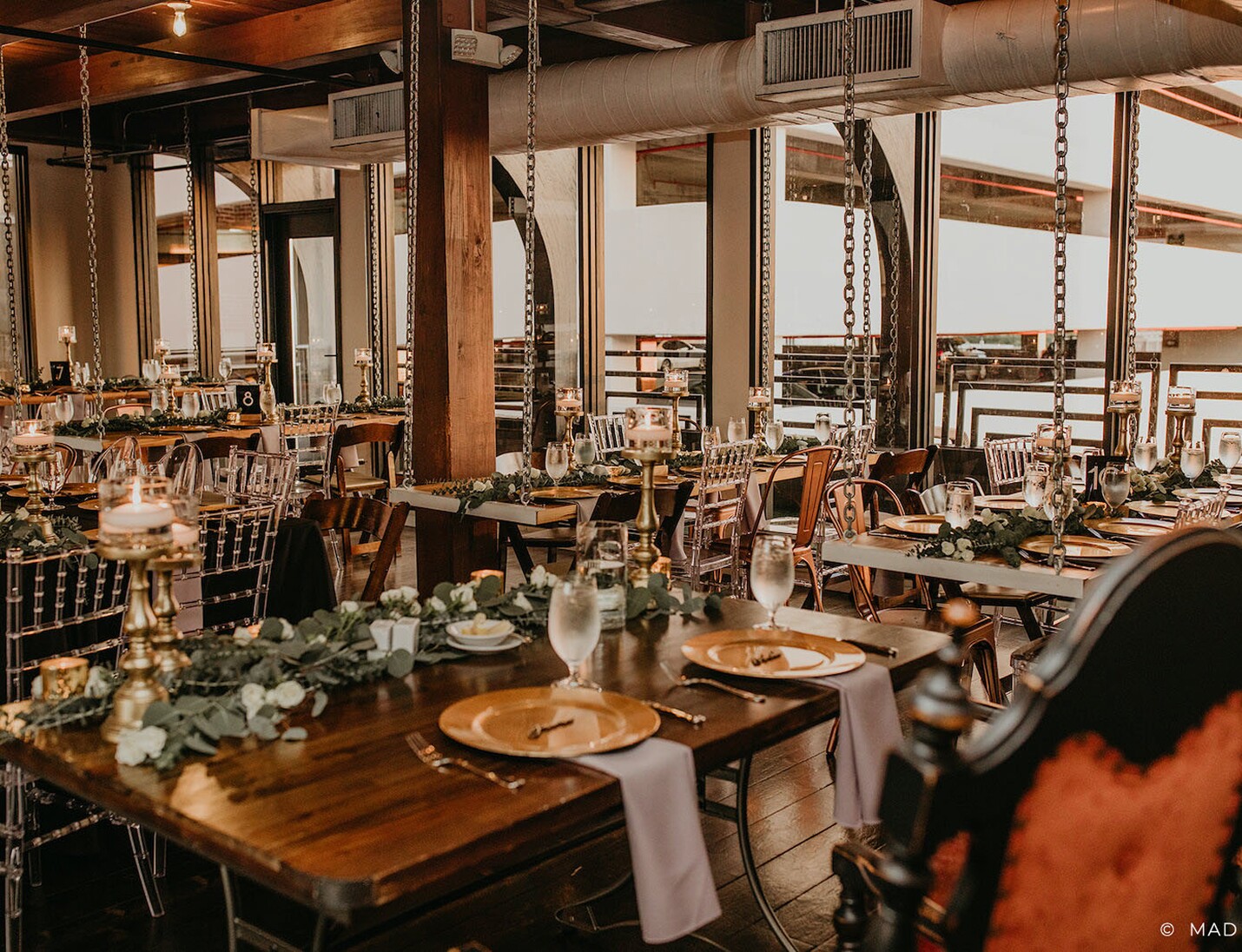 Warm industrial-style setup at Station House with wooden tables, candlelight decor and hanging chains for a rustic look
