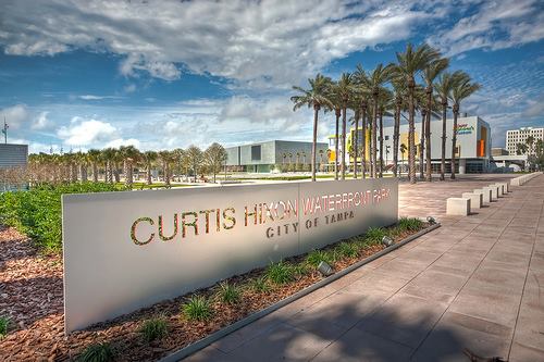 Entrance to Curtis Hixon Waterfront Park in Tampa with palm trees, modern buildings, and a bright blue sky