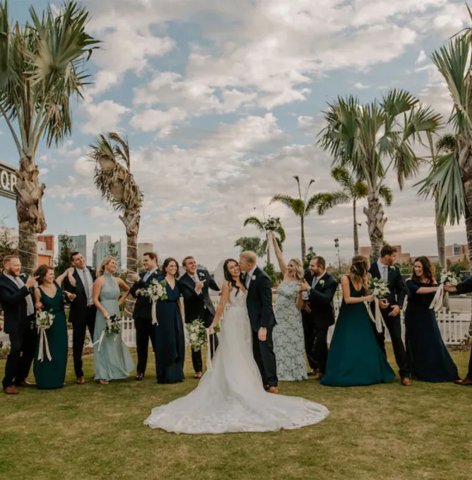Wedding party celebrating outdoors with palm trees and skyline at Armature Works lawn