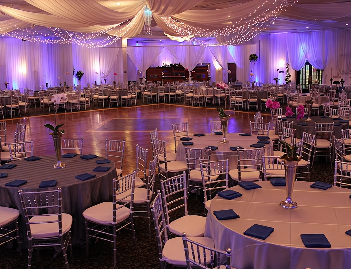 Elegant ballroom setup at Bayanihan Arts and Events Center with draped ceiling, uplighting, and round tables