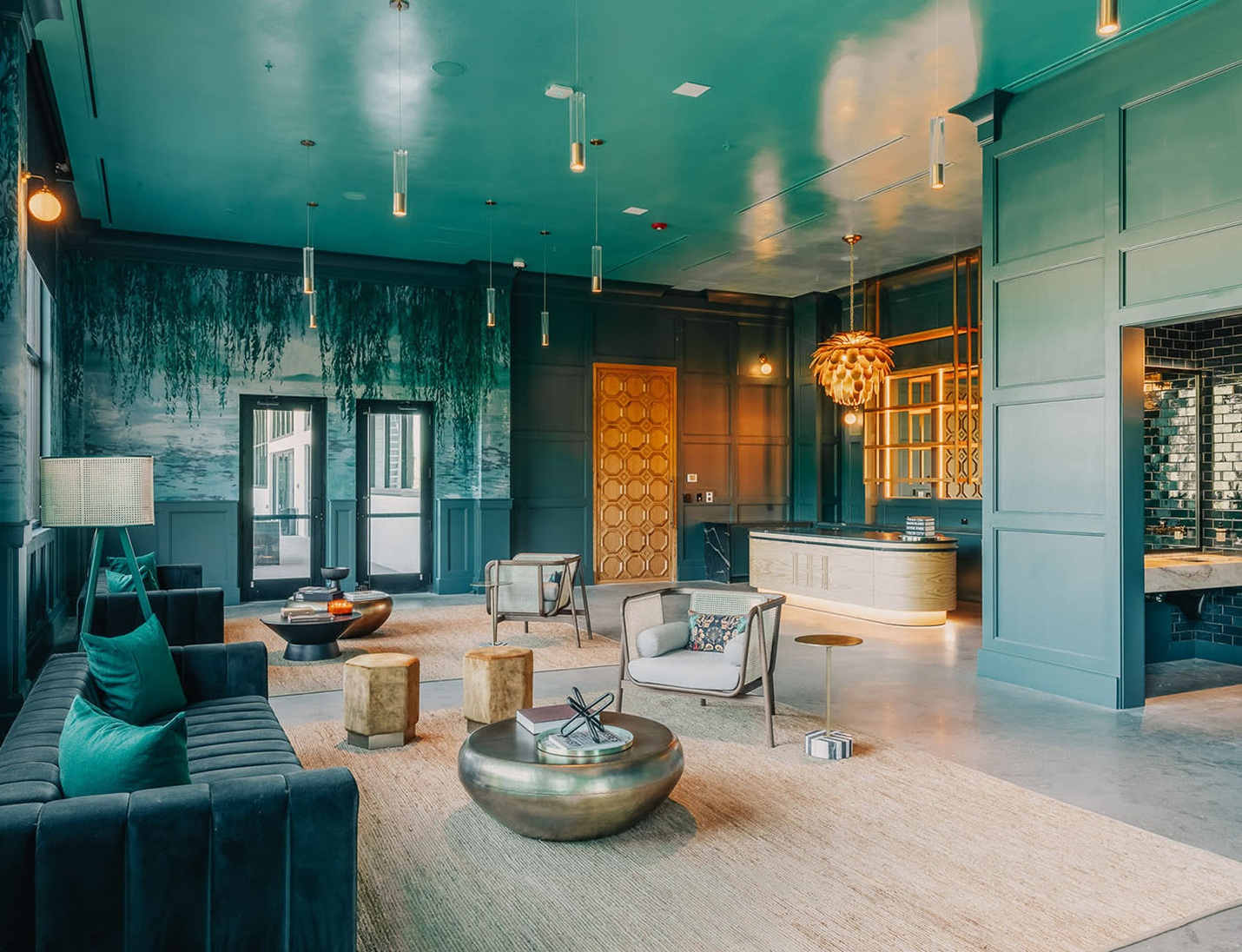 Modern lounge interior at Hyde House featuring teal walls, contemporary furniture, gold accents, and pendant lights