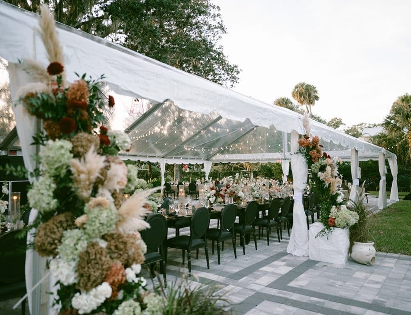 Elegant outdoor reception setup at Victoria 1883 with floral arrangements, long tables, and clear tent with lights