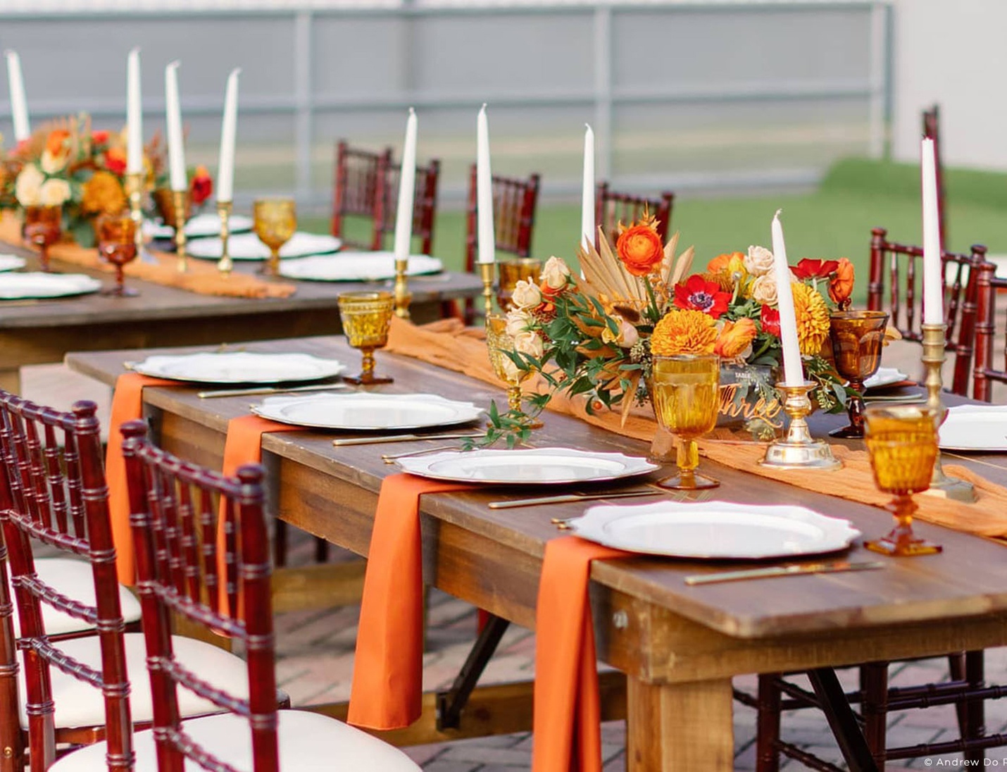 Outdoor wedding table setup at Kozuba & Sons Distillery with orange accents, candles, and floral centerpiece decor