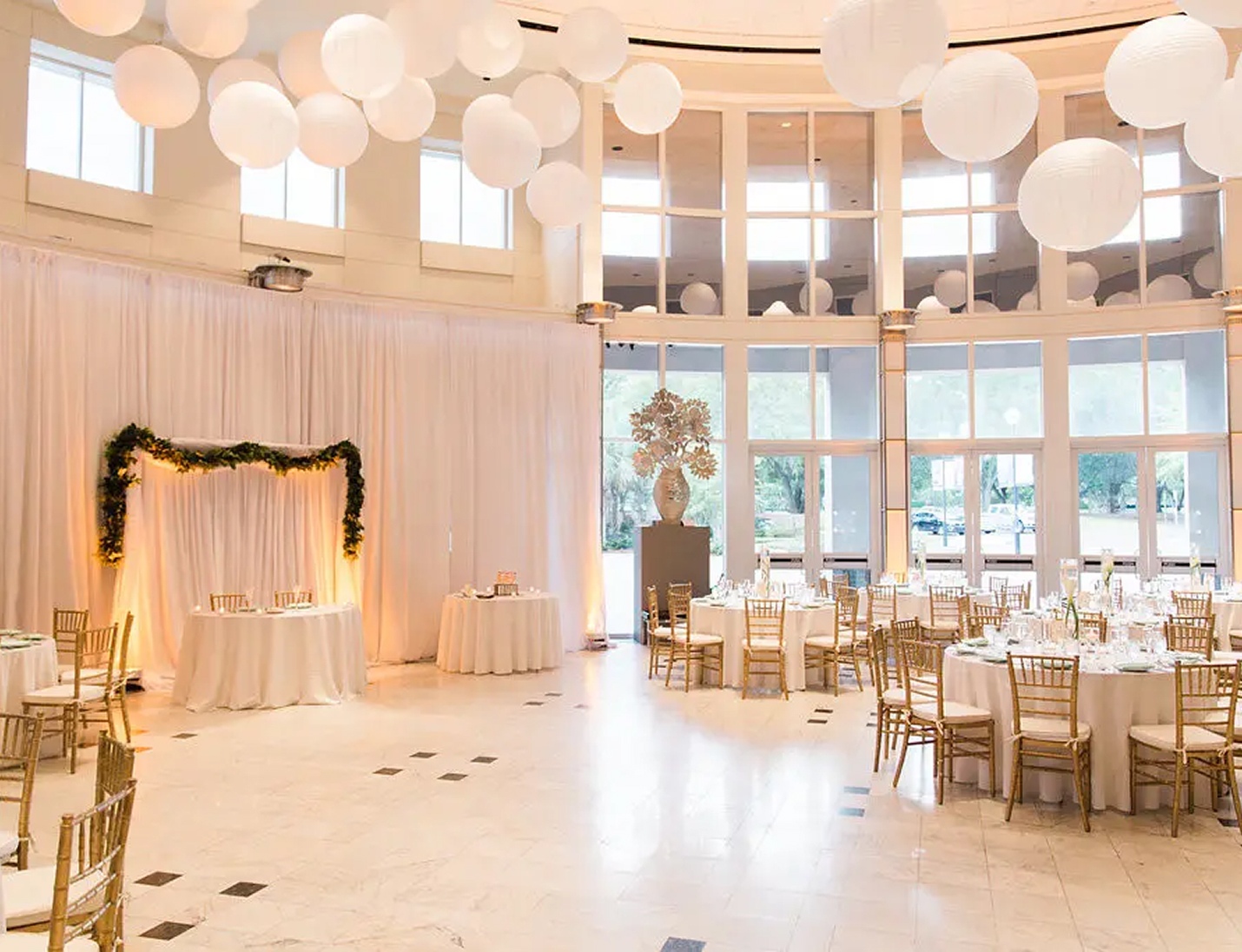 Elegant indoor wedding reception at Orlando Museum of Art with draped walls, round tables, and hanging lanterns