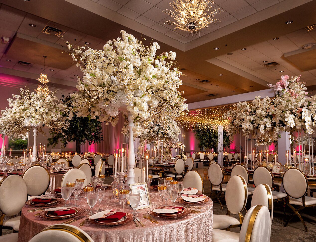 Luxurious wedding reception at Holy Trinity Center with grand floral arrangements, candles, and soft lighting