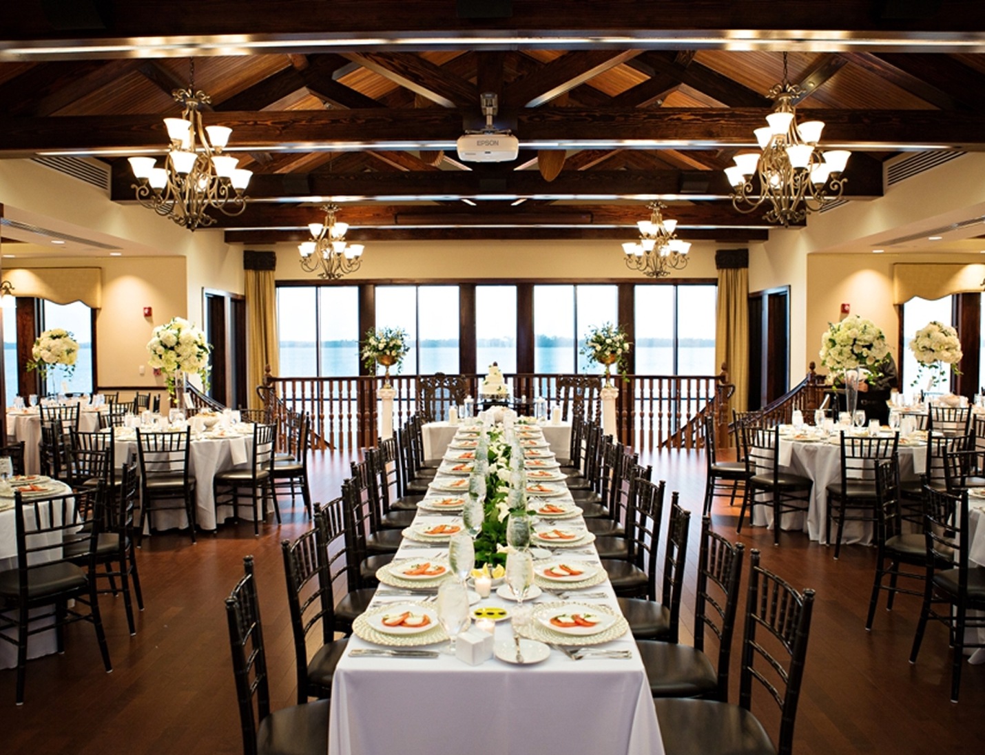 Indoor reception at Tavares Pavilion on the Lake with a long banquet table, floral centerpieces, and lake view windows