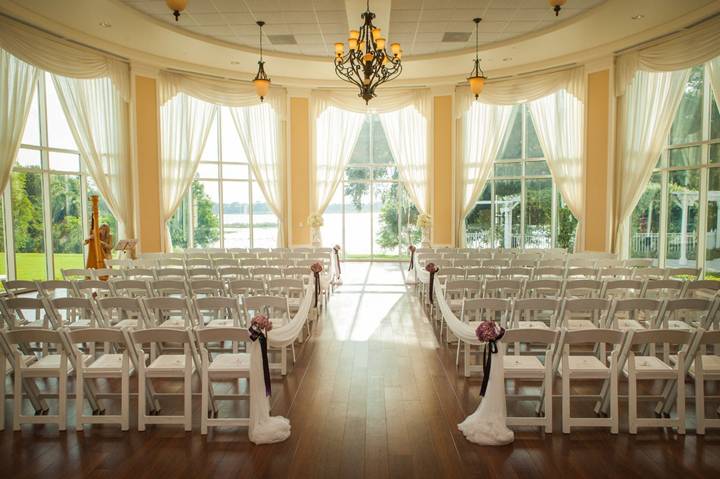 Indoor wedding ceremony setup at Lake Mary Events Center with large windows, draped curtains, and rows of white chairs