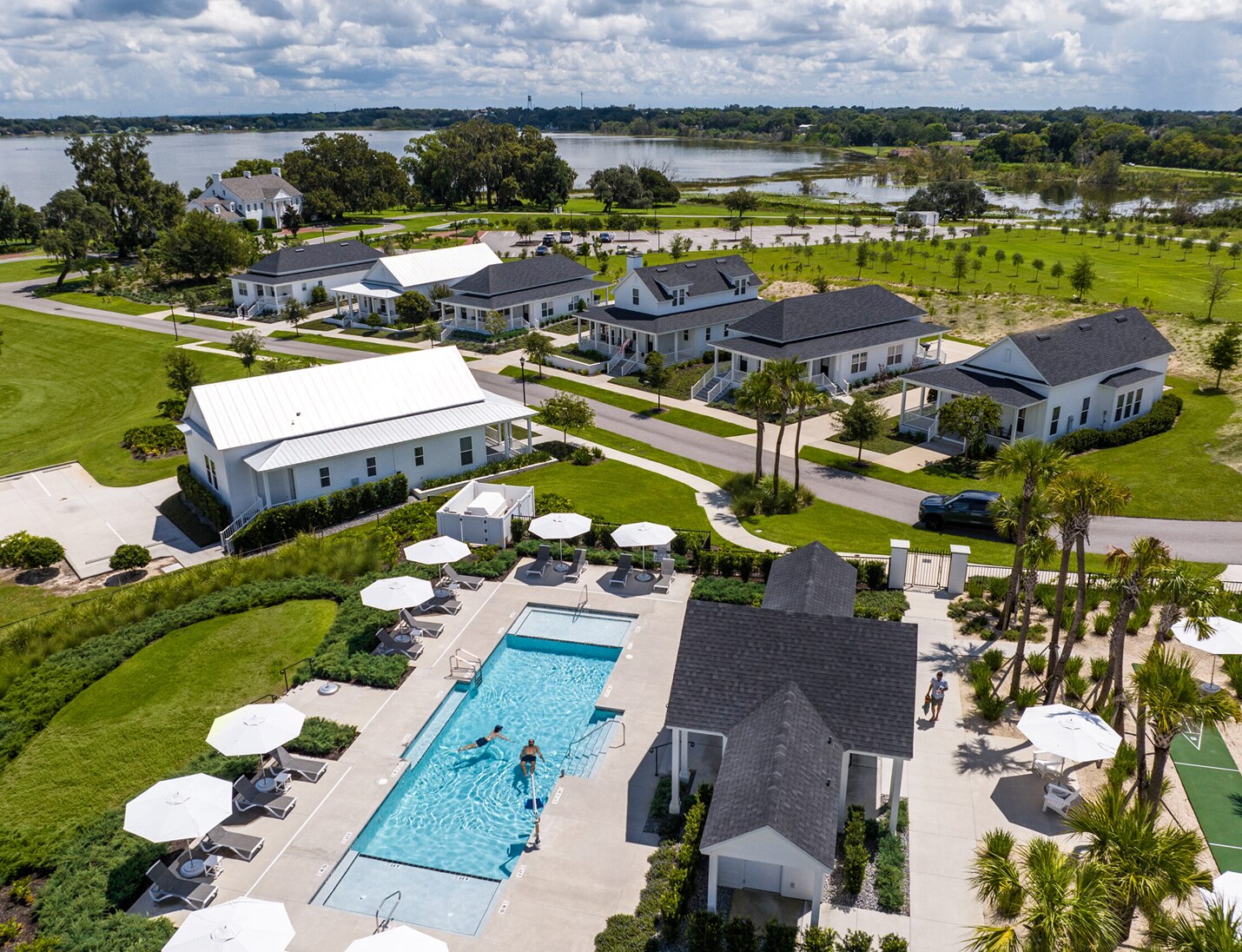 Aerial view of Adam’s Estate showing lakeside property with white cottages, outdoor pool, umbrellas, and green lawns