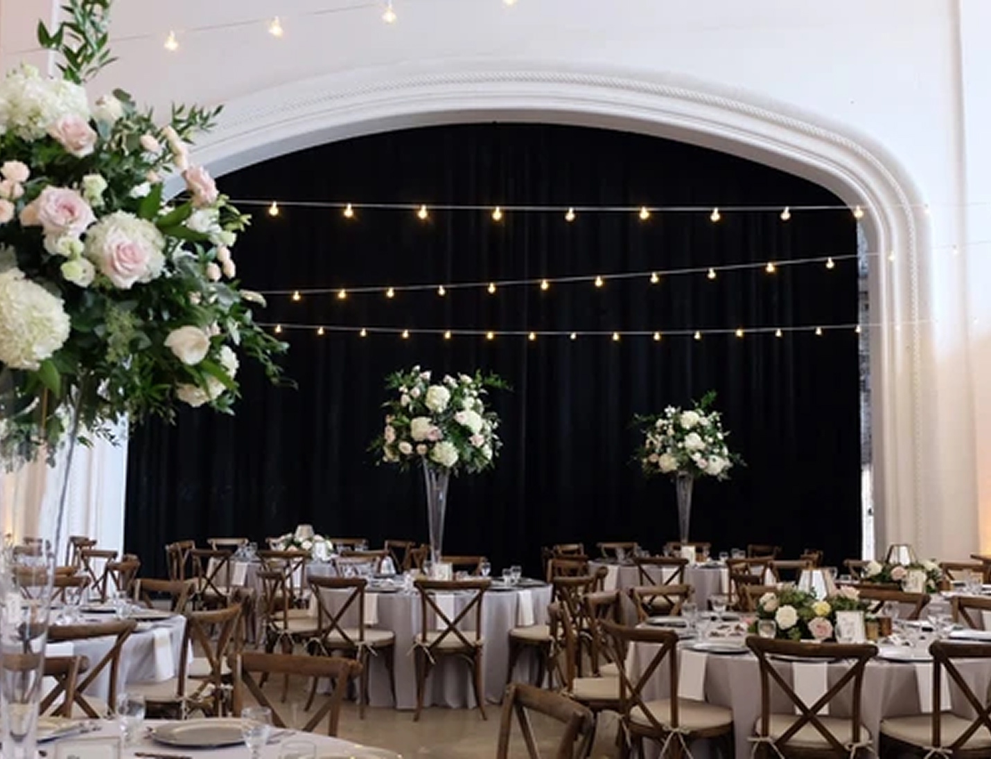 Indoor wedding reception at Rialto Theatre Tampa with white arch, string lights, and tall floral centerpieces