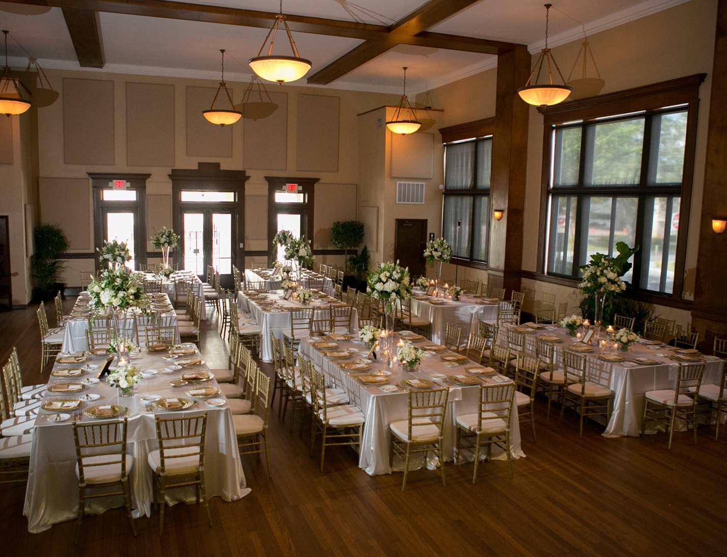 Formal setup at Junior League Sorosis Building with long white tables, gold chairs, floral décor, and soft lighting