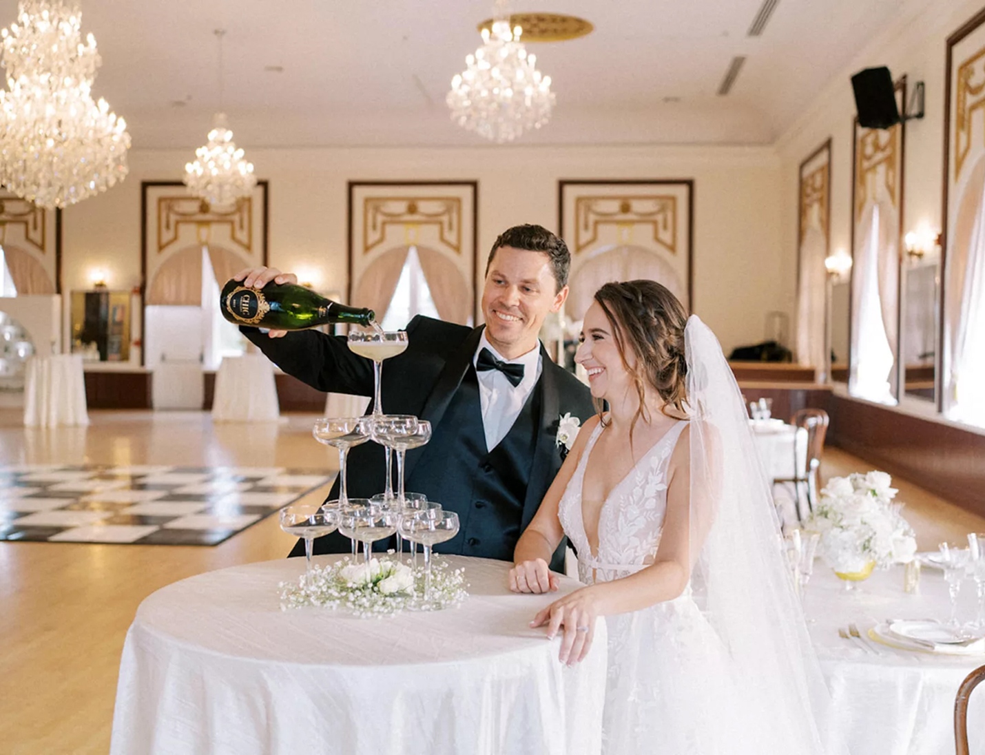 Wedding at Centro Asturiano de Tampa featuring chandeliers, a champagne tower, happy couple, and classic ballroom decor
