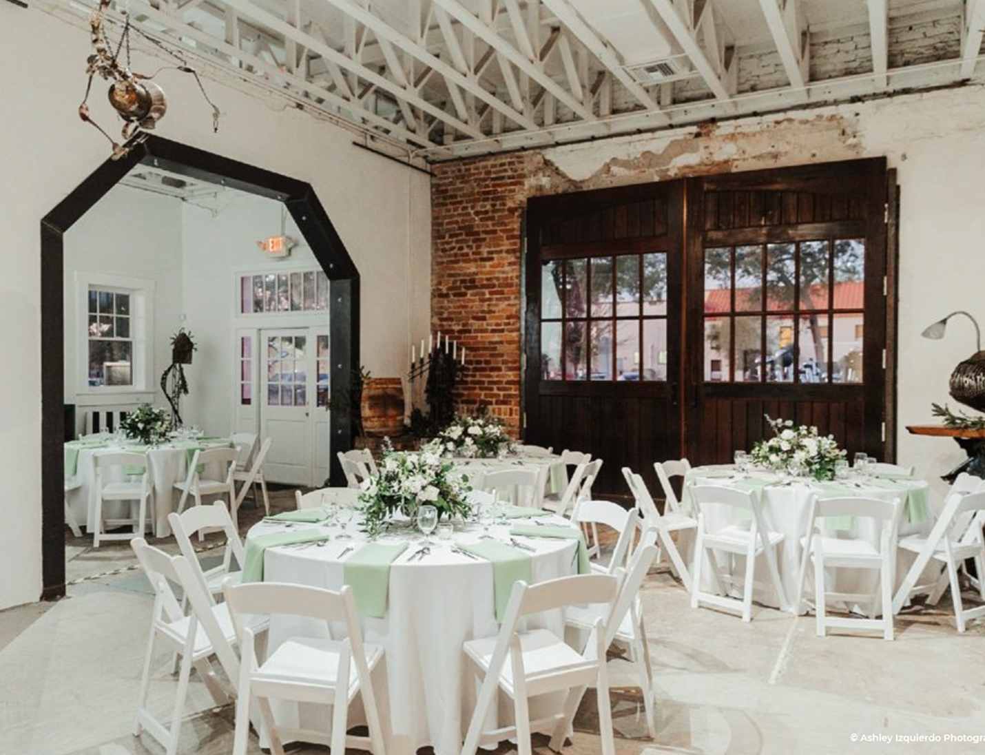 Industrial-style interior at Red Door No. 5 with white round tables, floral decor, and exposed brick walls