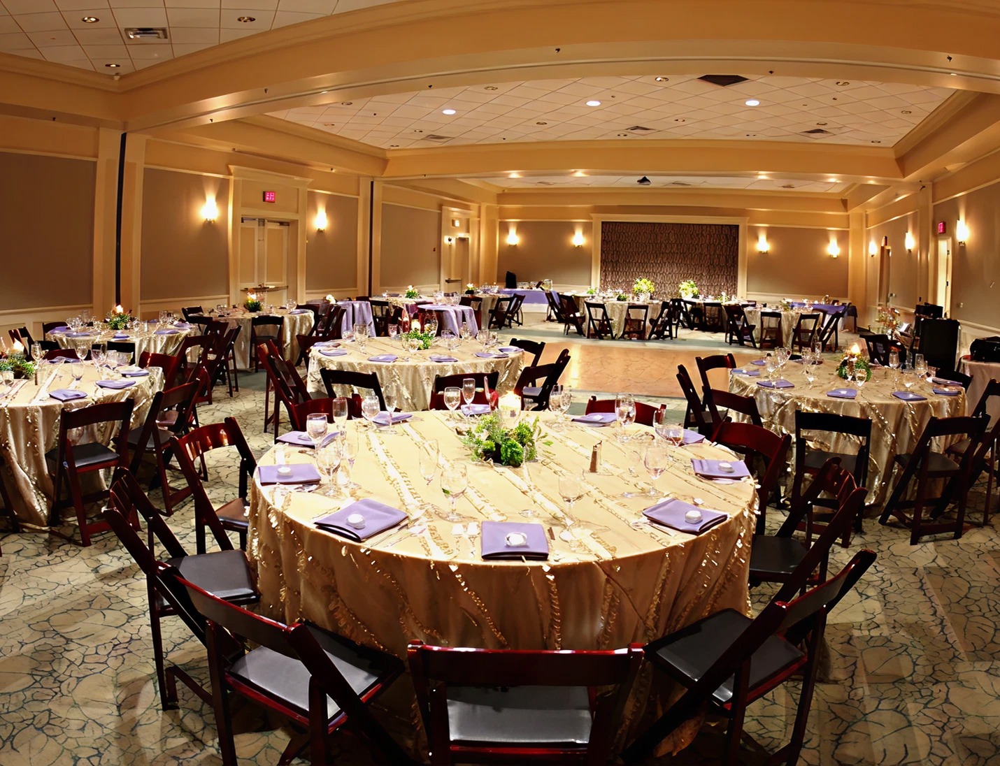Elegant indoor reception setup at Harry P. Leu Gardens with gold tablecloths, floral centerpieces, and warm lighting