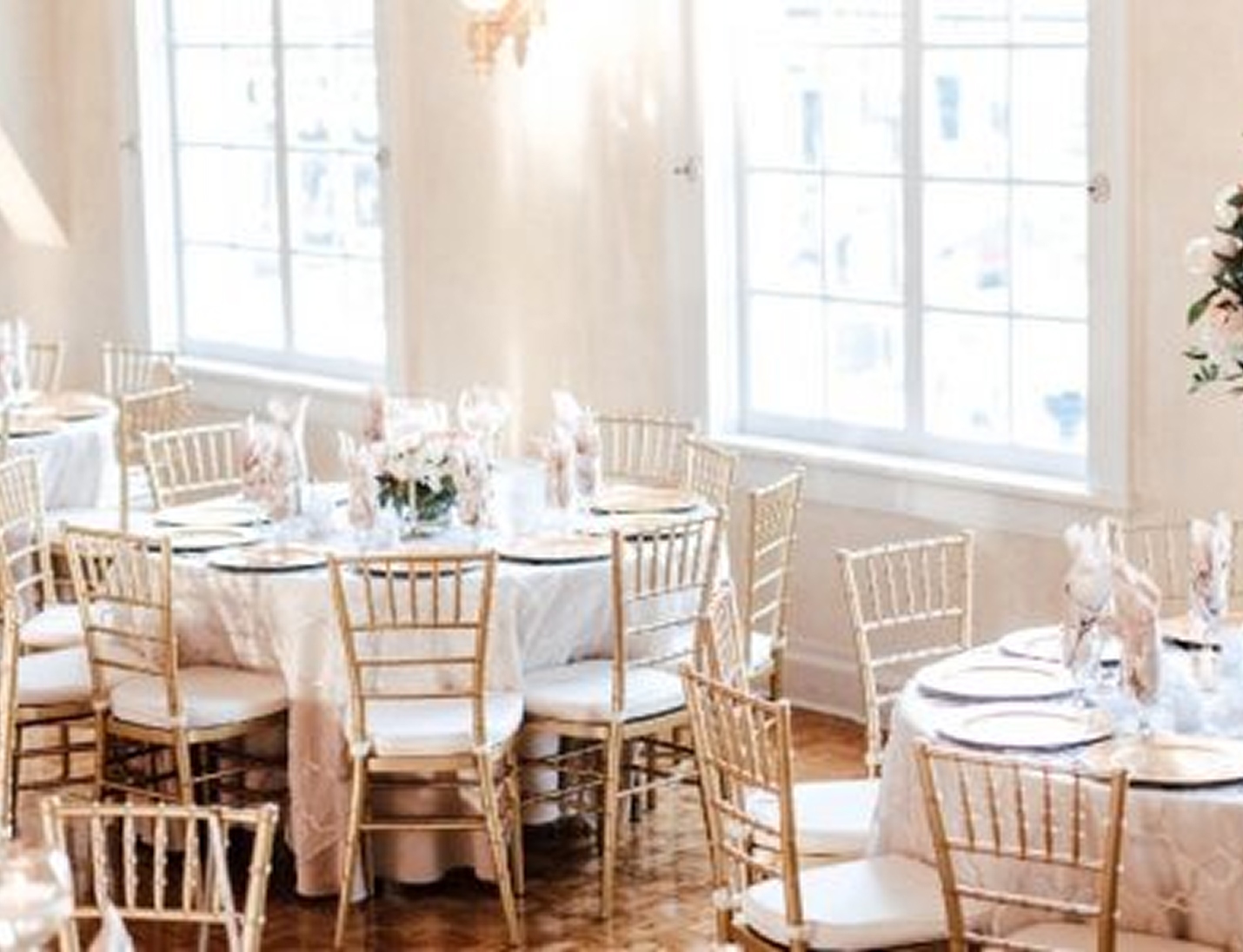 Elegant indoor wedding setup at The Italian Club of Tampa with white linens and soft daylight through large windows