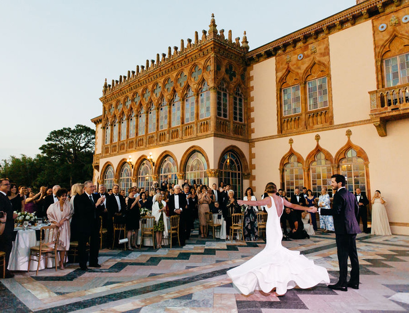 Bride and groom dancing during an outdoor reception at The John and Mable Ringling Museum of Art, surrounded by guests