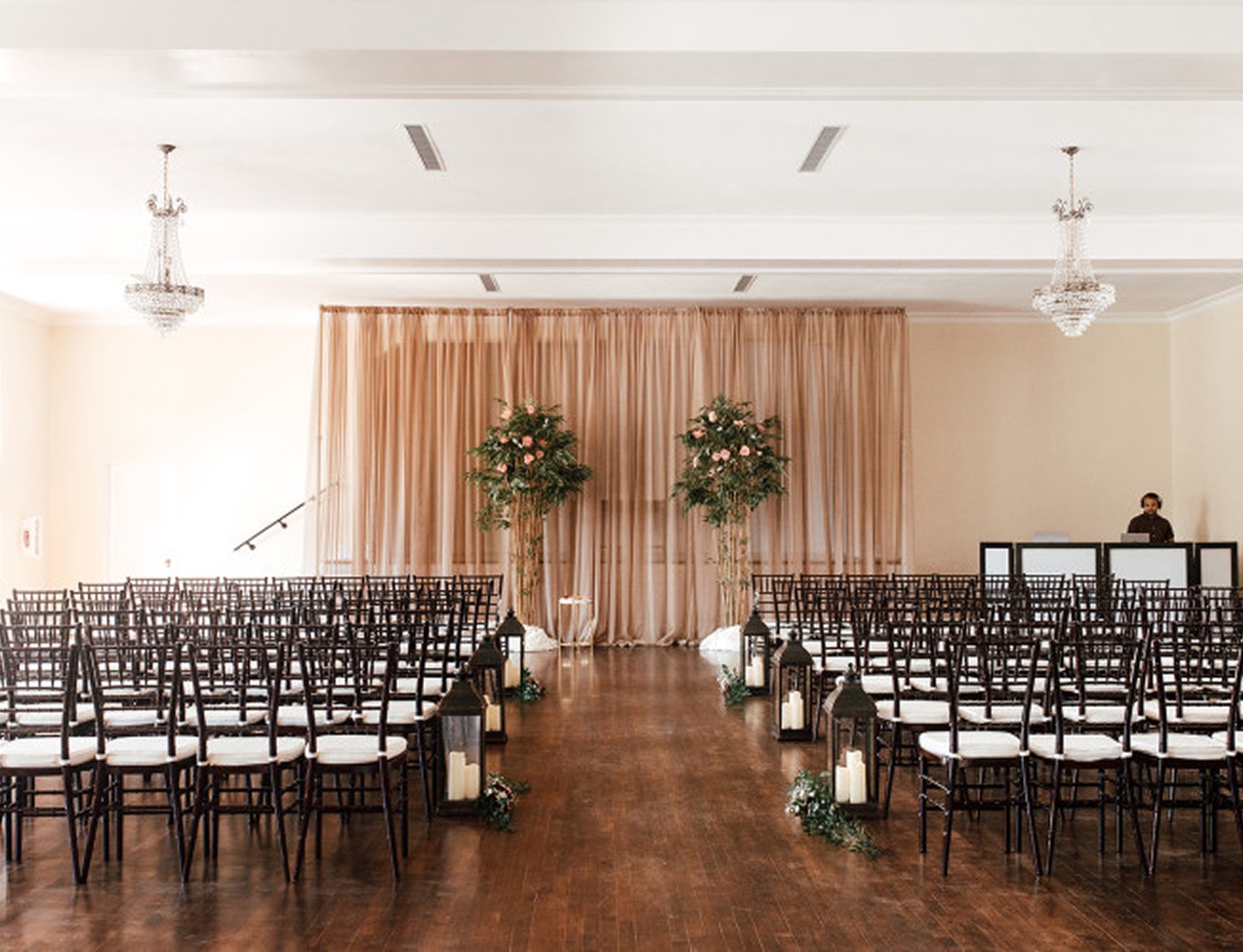 Elegant indoor ceremony setup at The Orlo House & Ballroom with floral arrangements, candles, and crystal chandeliers