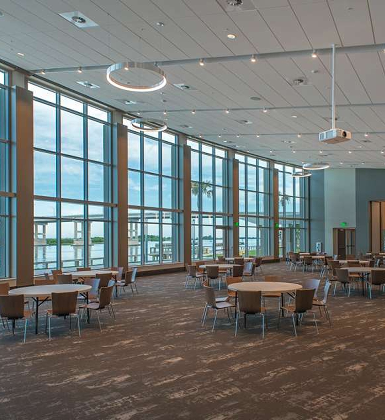 Modern ballroom at Brannon Civic Center featuring floor-to-ceiling windows with waterfront views and round tables