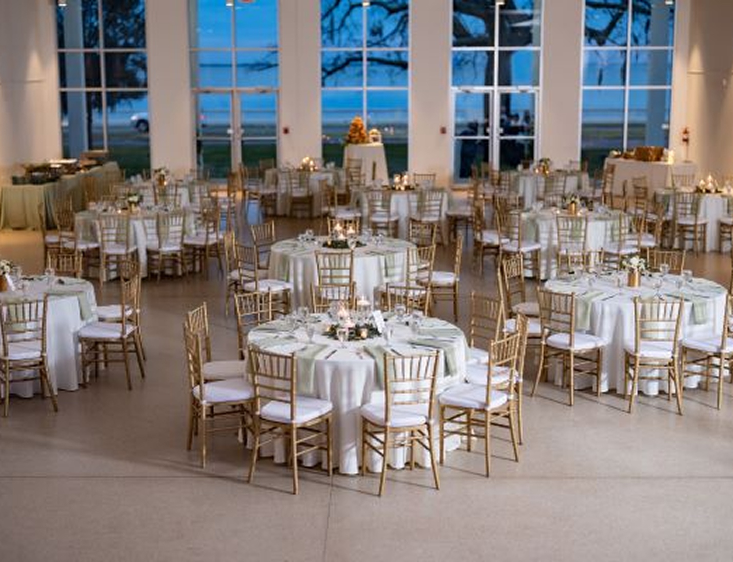 Tampa Garden Club reception setup with round tables, gold chairs, soft green accents and large window views