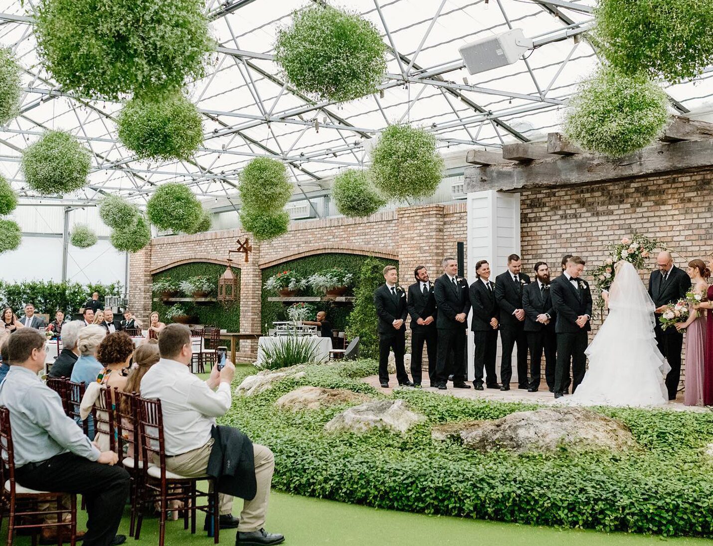 Hardeman’s Secret Garden wedding ceremony with hanging greenery, and guests watching the couple exchange vows