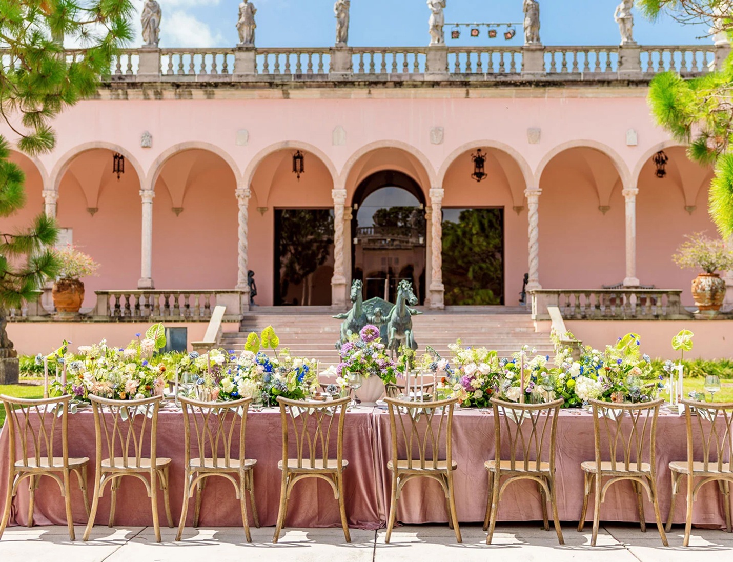 Elegant outdoor reception table with lush floral centerpieces in front of The John and Mable Ringling Museum of Art