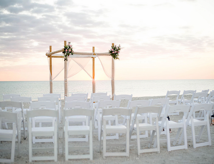 Beach wedding ceremony setup with a floral arch overlooking the ocean at Lions Club Beach House St. Petersburg
