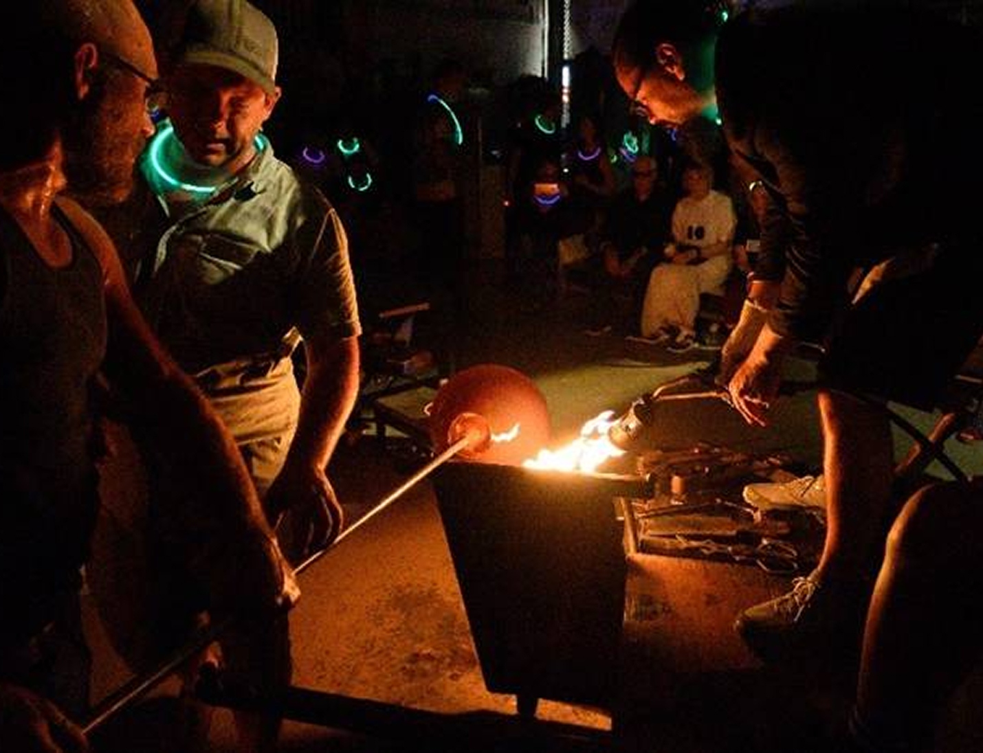Glassblowing demonstration at Morean Glass Studio & Hotshop, with artists shaping molten glass under warm firelight