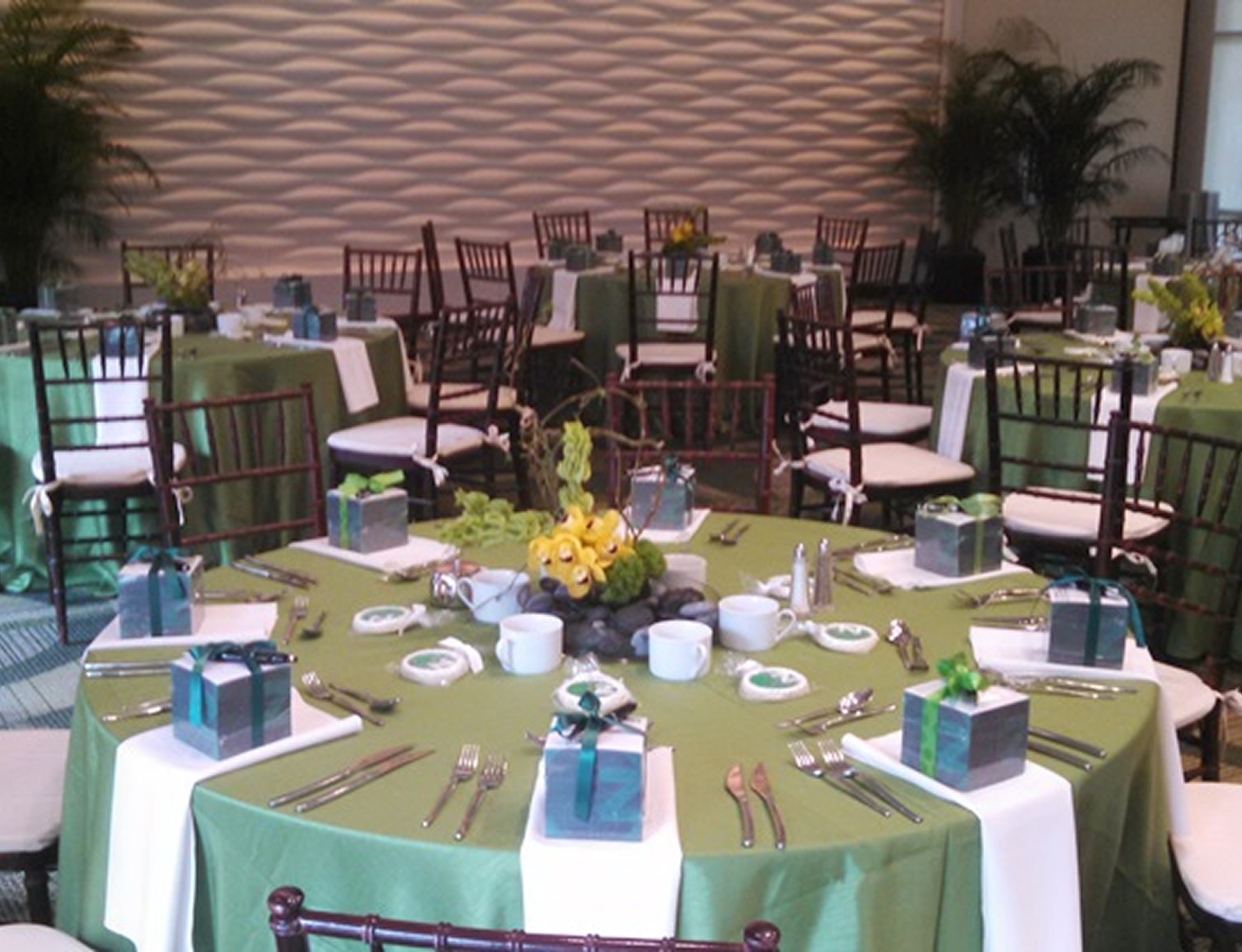 Reception setup at USF Gibbons Alumni Center with green linens, white runners, floral centerpiece, and dark wood chairs