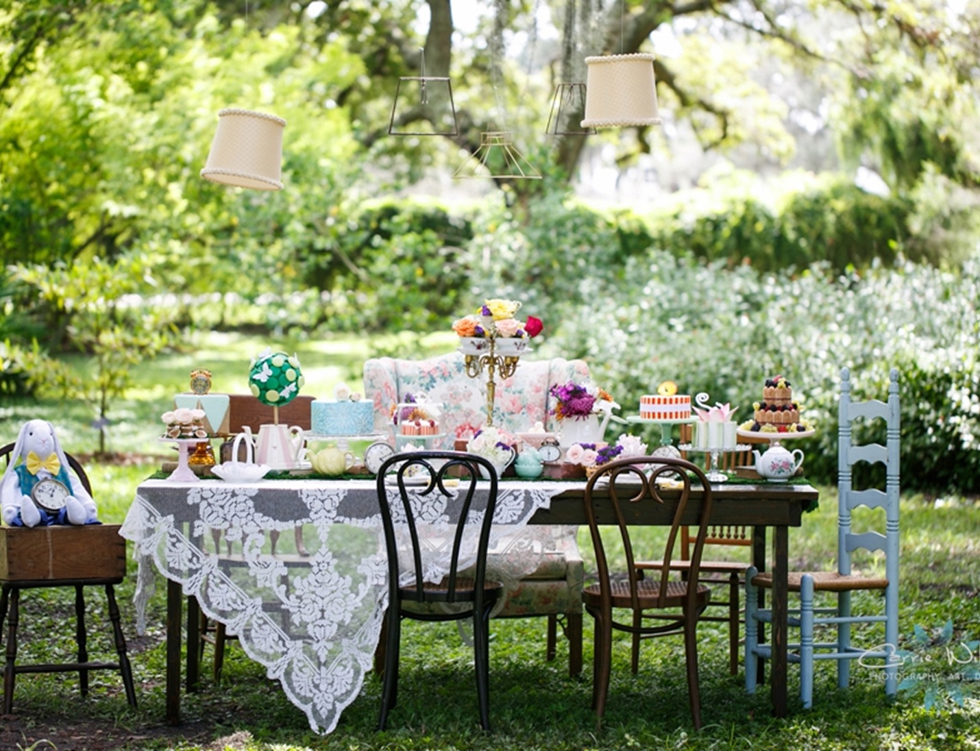 Whimsical garden tea party table with lace, vintage chairs, pastel treats, and florals at USF Botanical Gardens