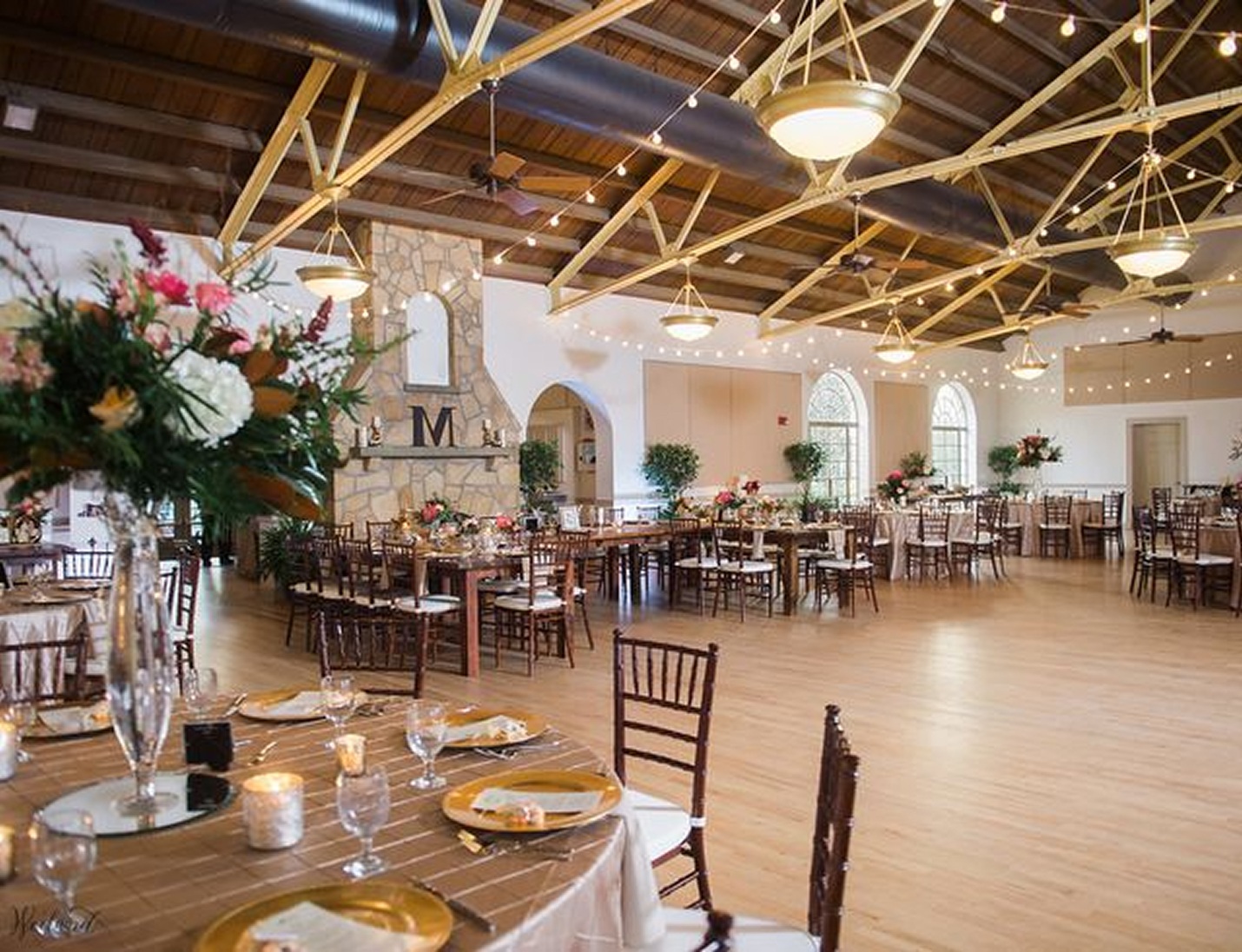 Magnolia Building reception setup with warm lighting, wooden beams, floral centerpieces, and elegant banquet tables