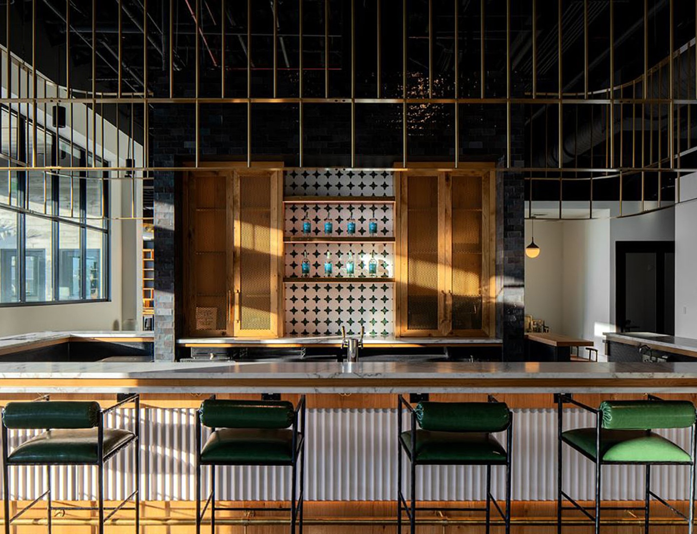 Modern bar space at Hyde House featuring green barstools, a marble countertop, and wooden cabinetry
