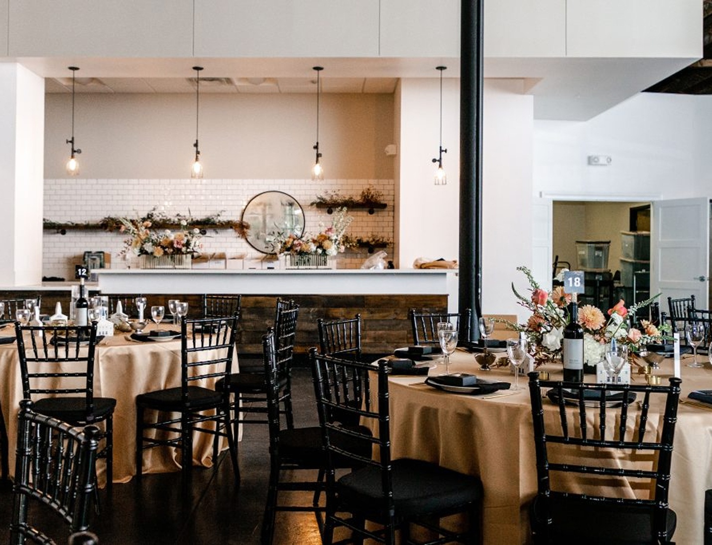 Elegant reception setup at Haus 820 with round tables, black chairs, floral centerpieces, and a modern white backdrop