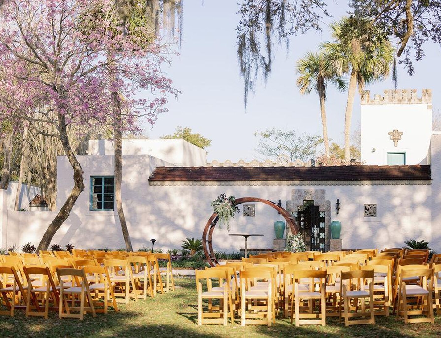Outdoor ceremony setup at Art & History Museums - Maitland with wooden chairs, circular arch, and historic courtyard