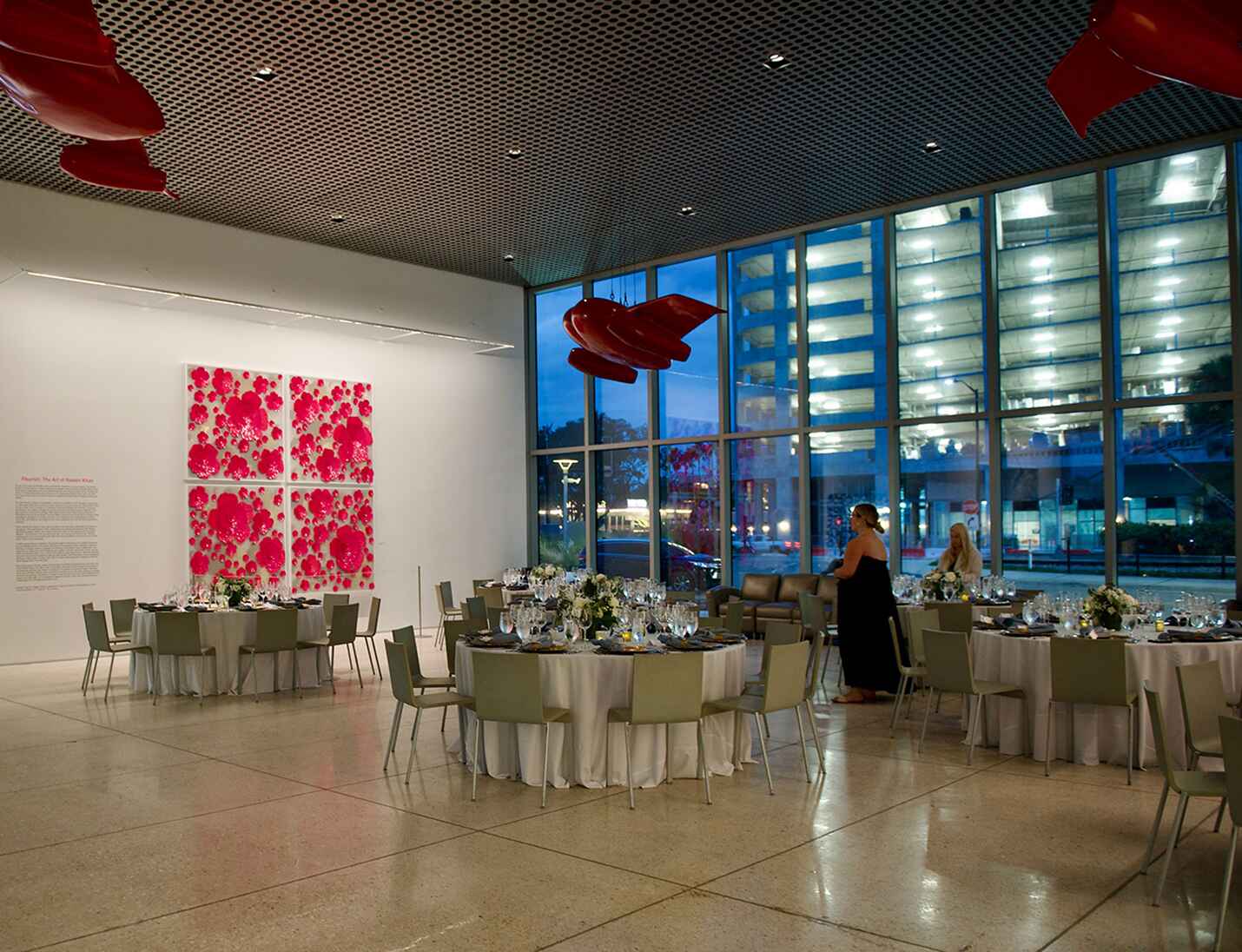 Elegant reception setup at Tampa Museum of Art with round tables, modern chairs, large windows, and bold red art accents