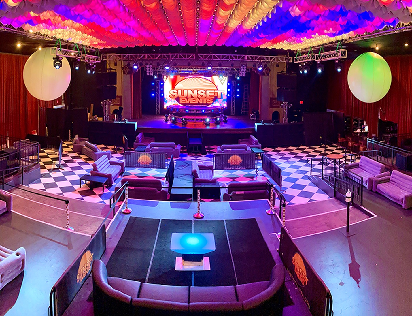 Vibrant event setup at The Ritz Ybor with colorful ceiling, lounge seating, stage lighting, and checkered flooring