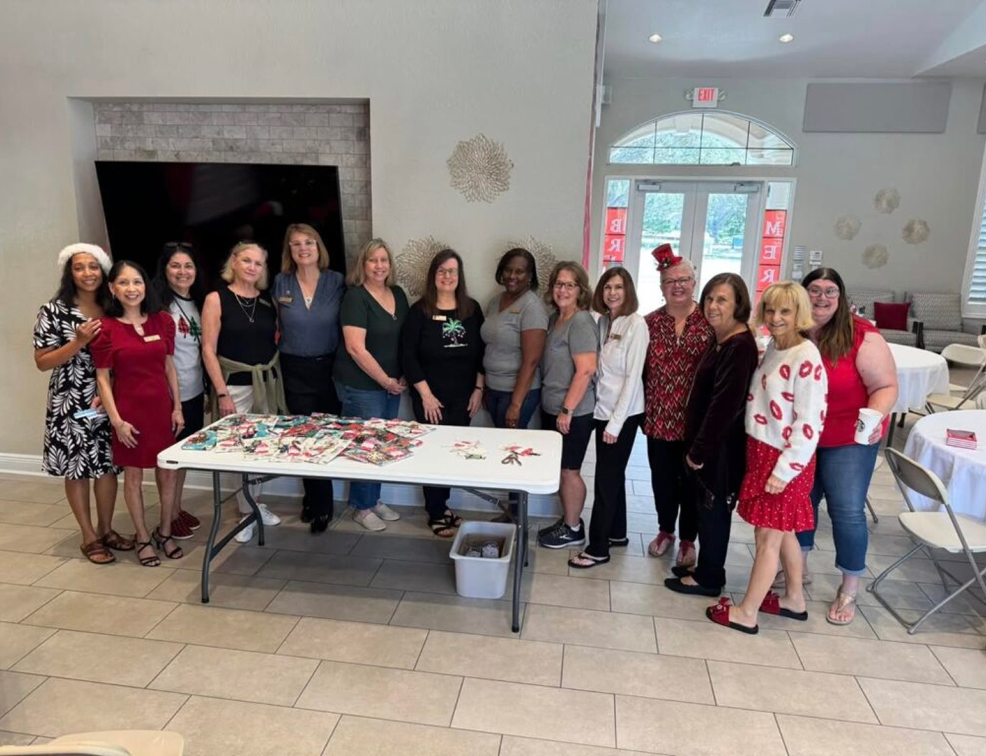 Group of women posing together around a table during an event at GFWC Tampa Women’s Club, inside a bright gathering room