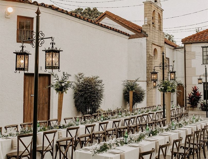 Wedding reception with long banquet tables and greenery decor in the courtyard at The Bishop Museum of Science and Nature