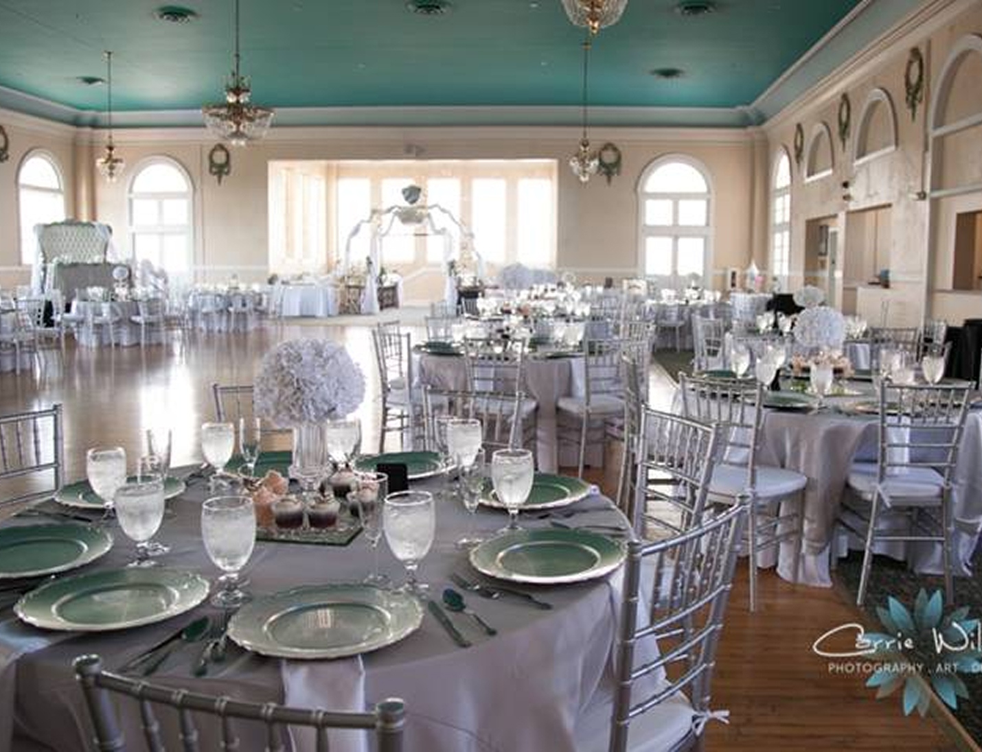 Elegant wedding reception at The Cuban Club with silver chairs, round tables, white floral centerpieces, and soft light