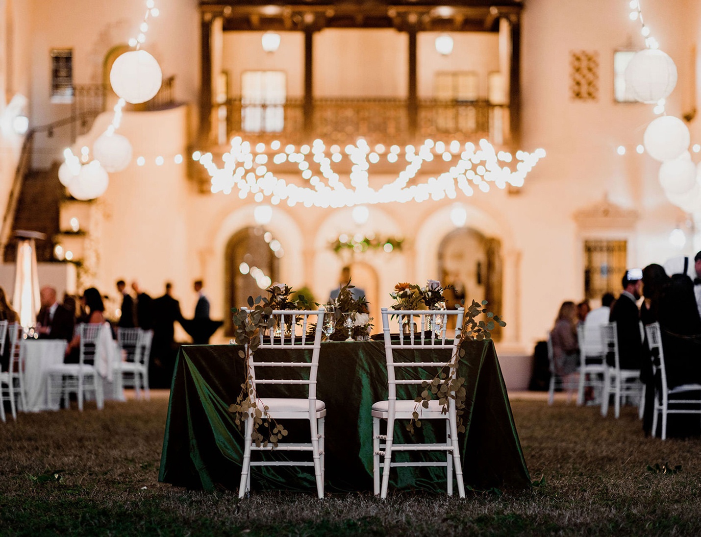 Romantic outdoor reception at Powel Crosley Estate with string lights and greenery-decorated sweetheart table