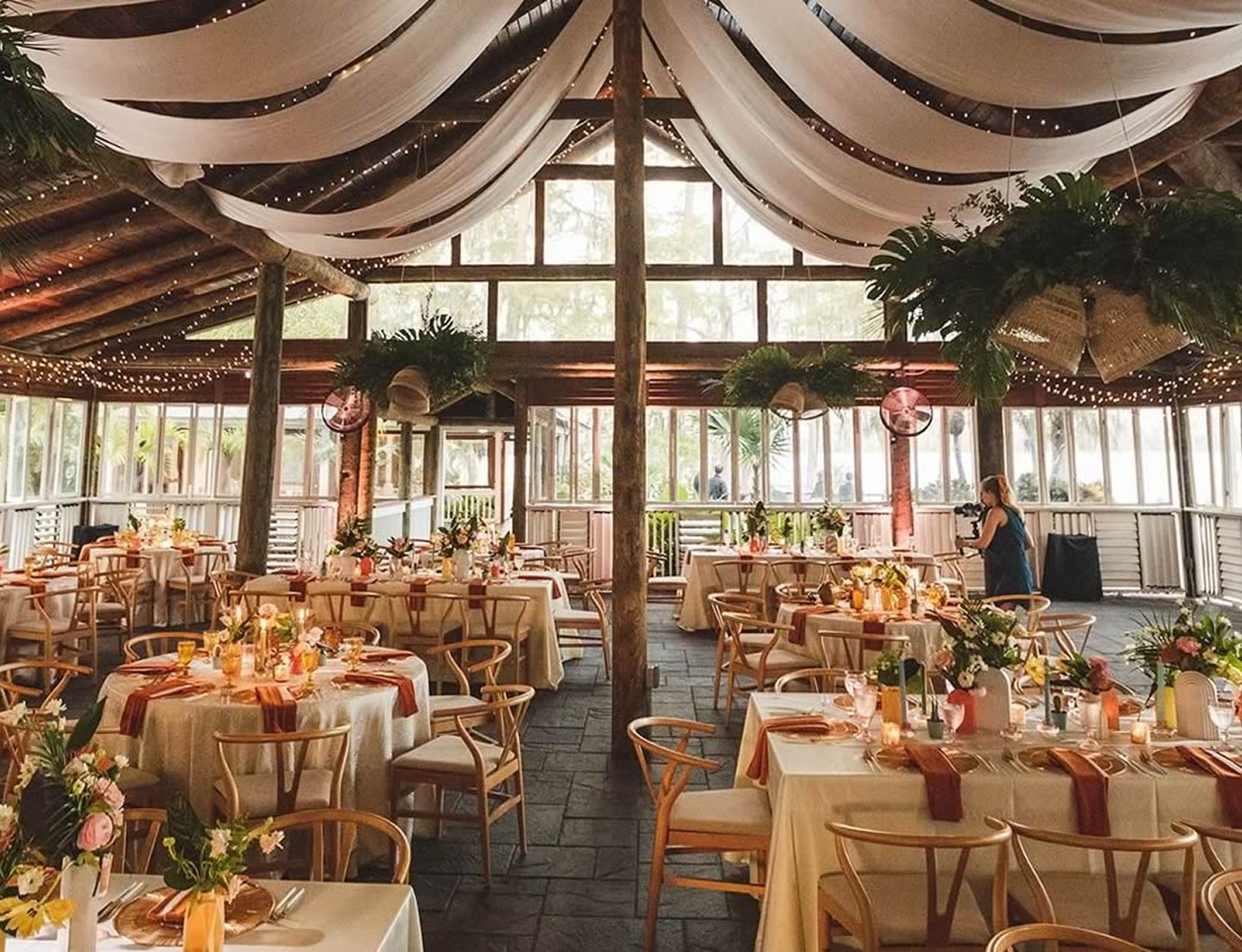 Wooden venue setup with draped ceiling, round tables, and wooden chairs arranged for an event at Paradise Cove - Orlando