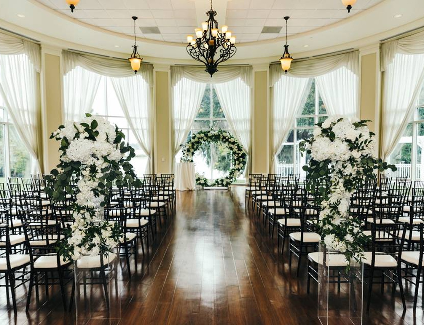 Lake Mary Events Center, a wedding hall with tall white floral displays, black chairs, and bright windows