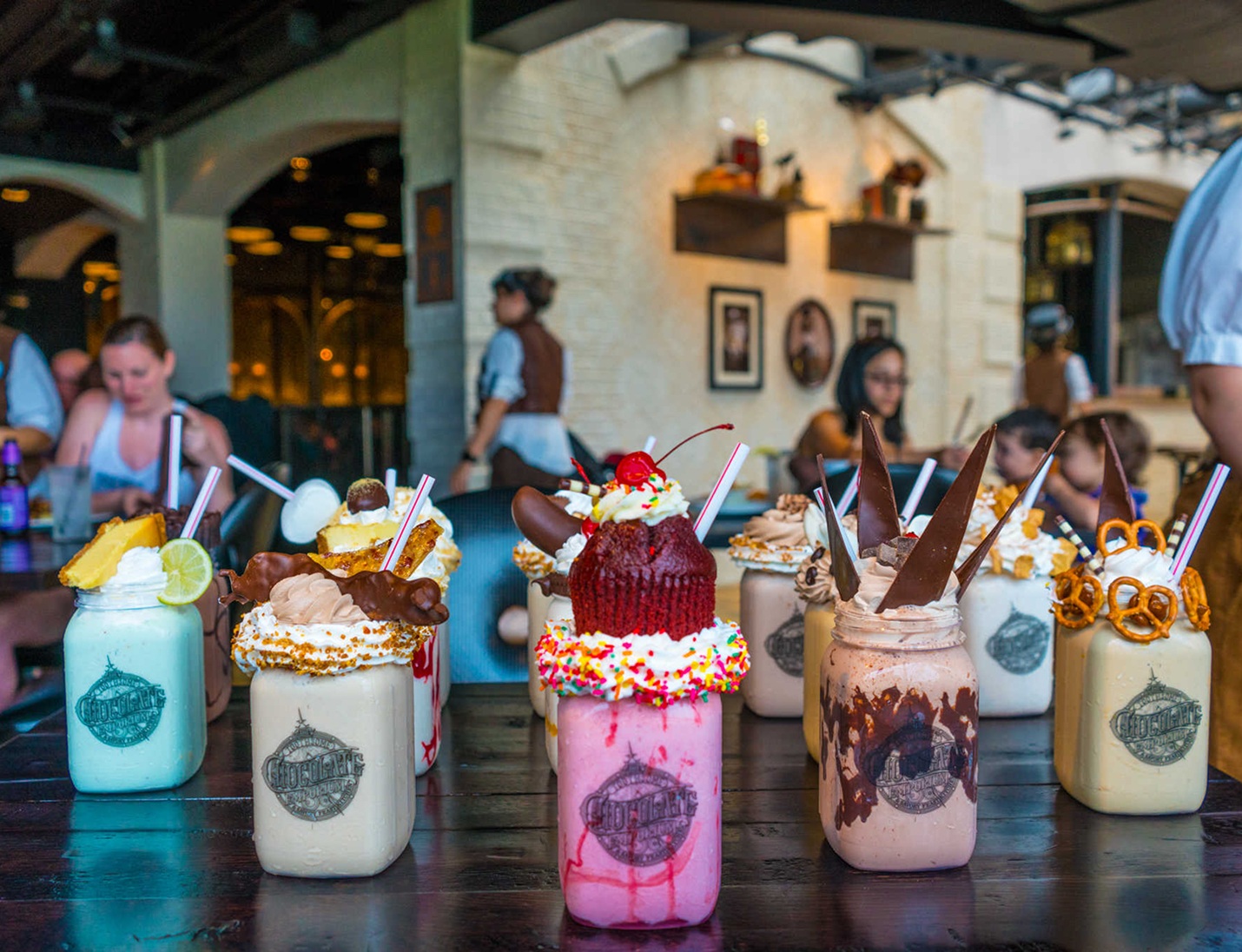 Mason jars filled with colorful milkshakes topped with cake, candy, and chocolate treats at the Chocolate Factory