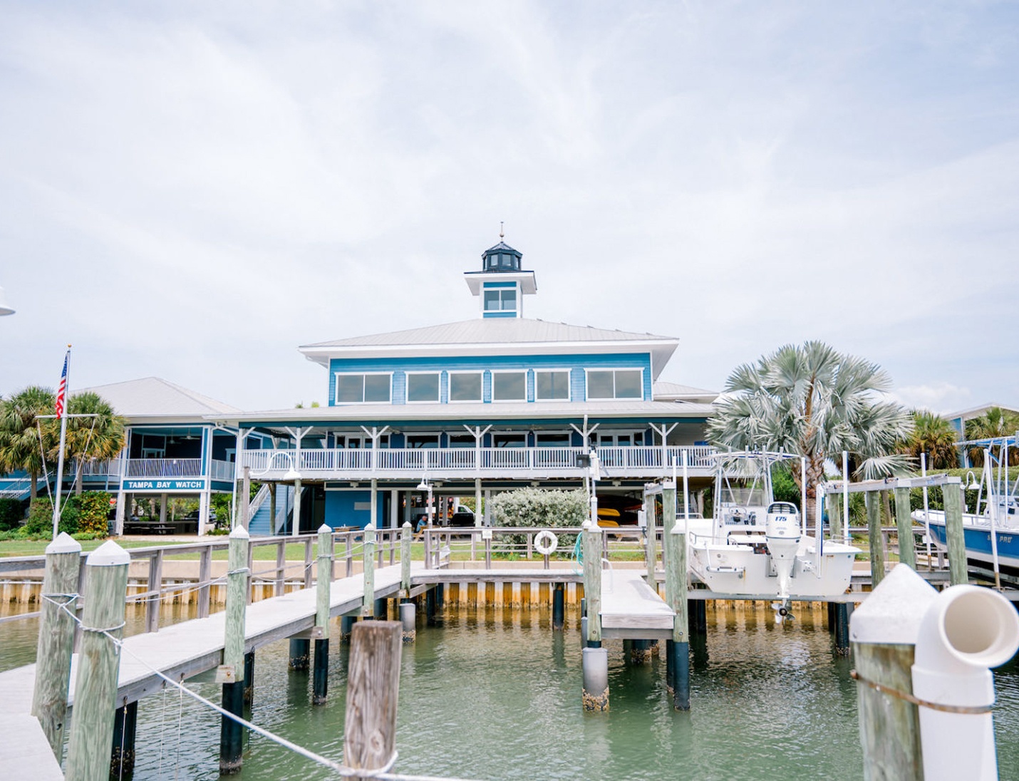 Tampa Bay Watch, a blue waterfront venue with boat docks, white railings, palm trees, and a central tower