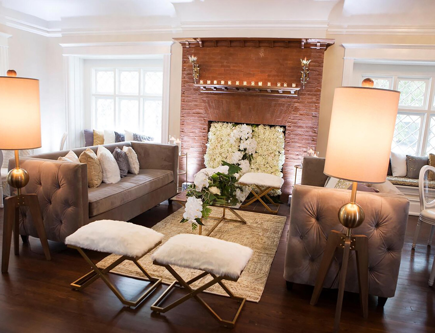 Elegant parlor with tufted sofas, a fireplace, floral decor, and gold lamps for seating at The Orlo House & Ballroom