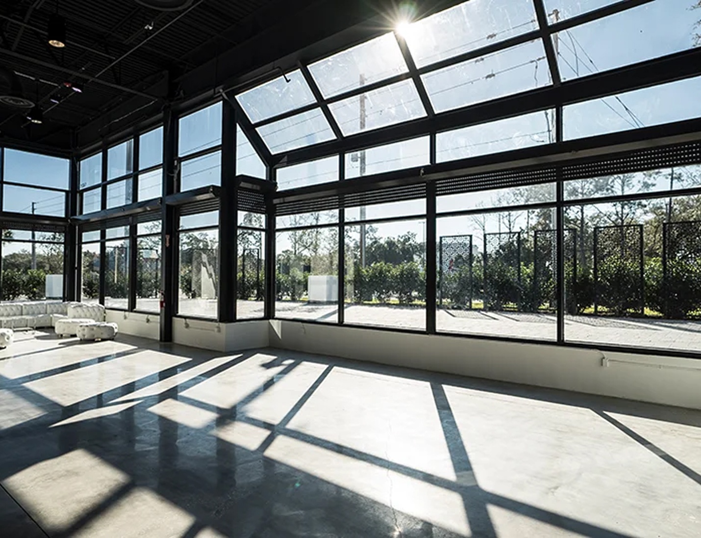 Modern indoor space at Canvas Event Venue with floor-to-ceiling windows, concrete floors, and abundant natural light