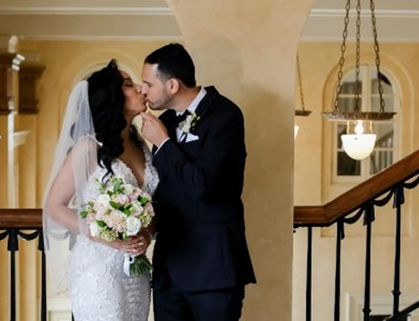 Bride and groom sharing a kiss on the balcony at The Italian Club of Tampa, holding a floral bouquet