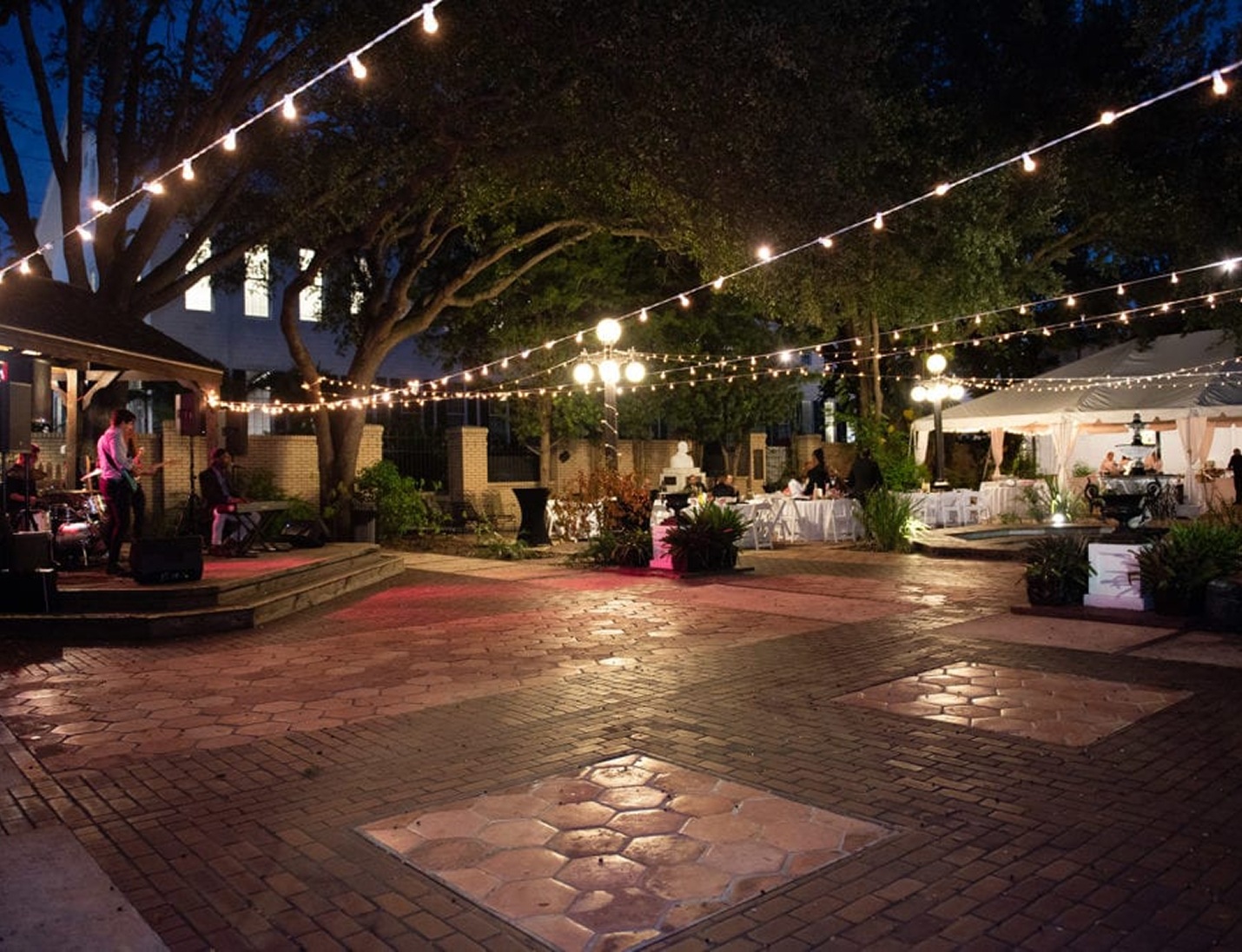 Outdoor evening event at Ybor City Museum State Park with string lights, live music, seating areas, and garden ambiance