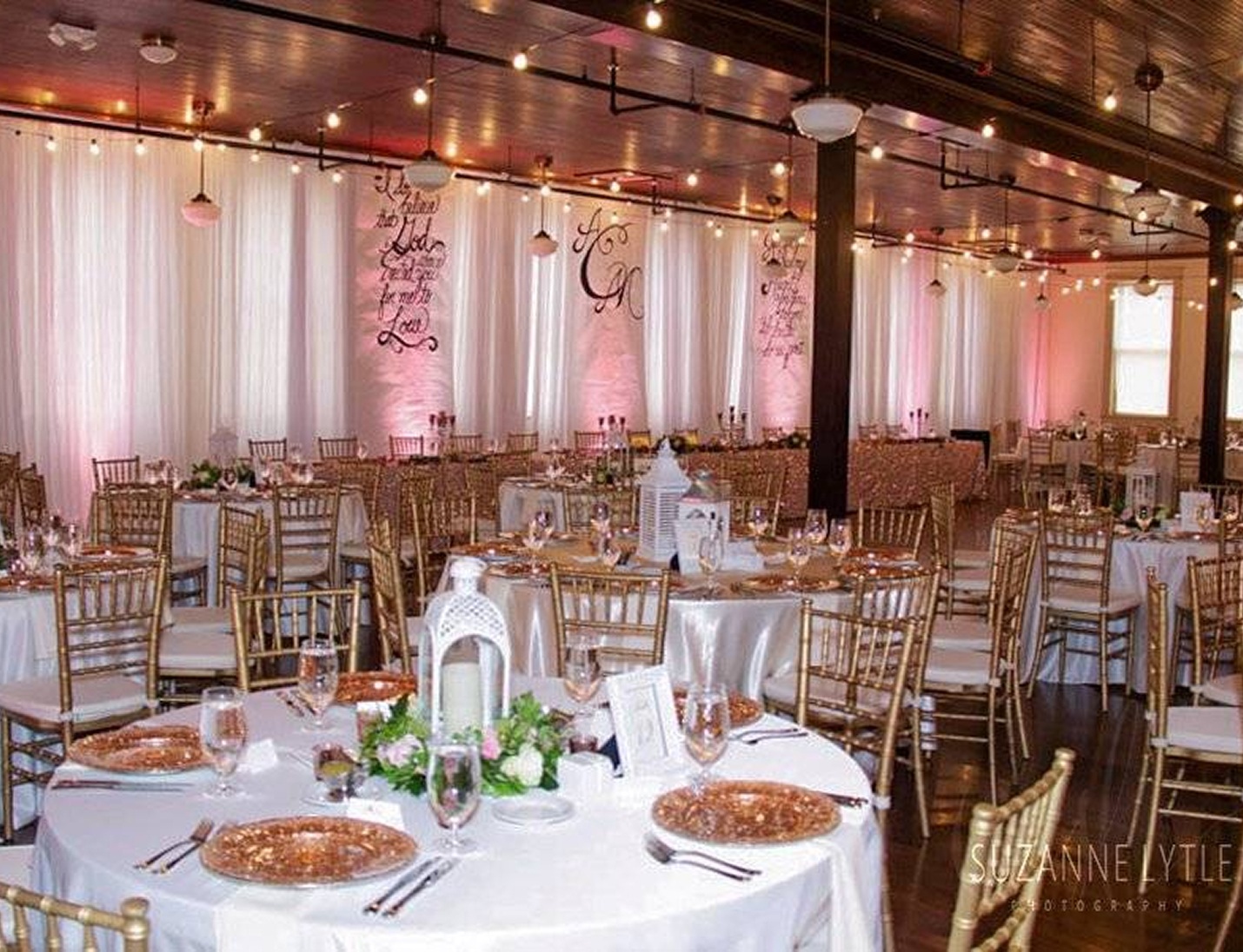Elegant reception setup at Tampa Firefighters Museum with round tables, draped walls, and warm string lighting