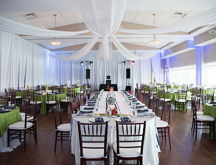 Elegant reception setup at St. Pete Beach Community Center with draped ceiling fabric, round tables, and soft uplighting