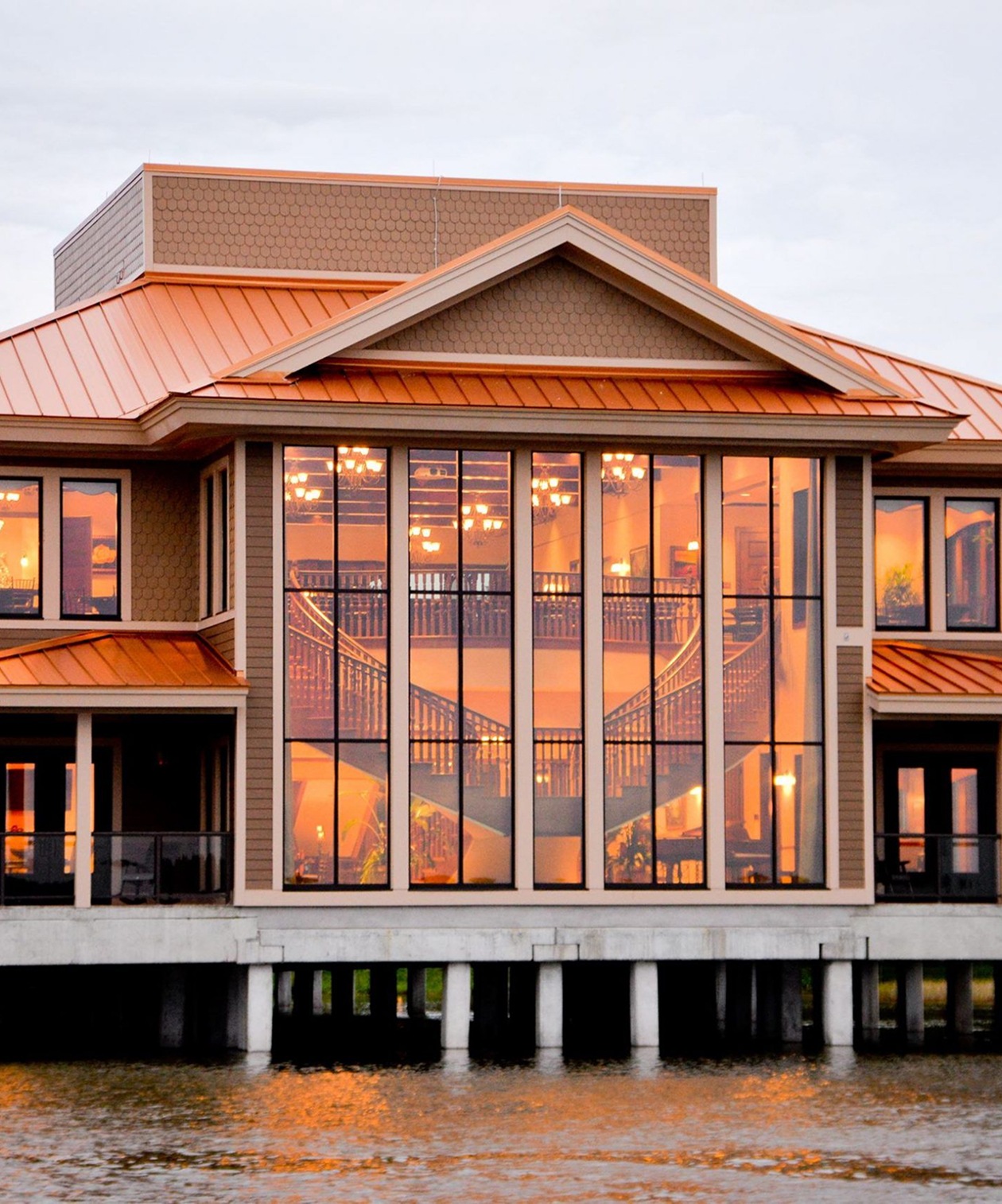 Waterfront venue with grand windows reflecting warm interior lights and staircase views at Tavares Pavilion on the Lake