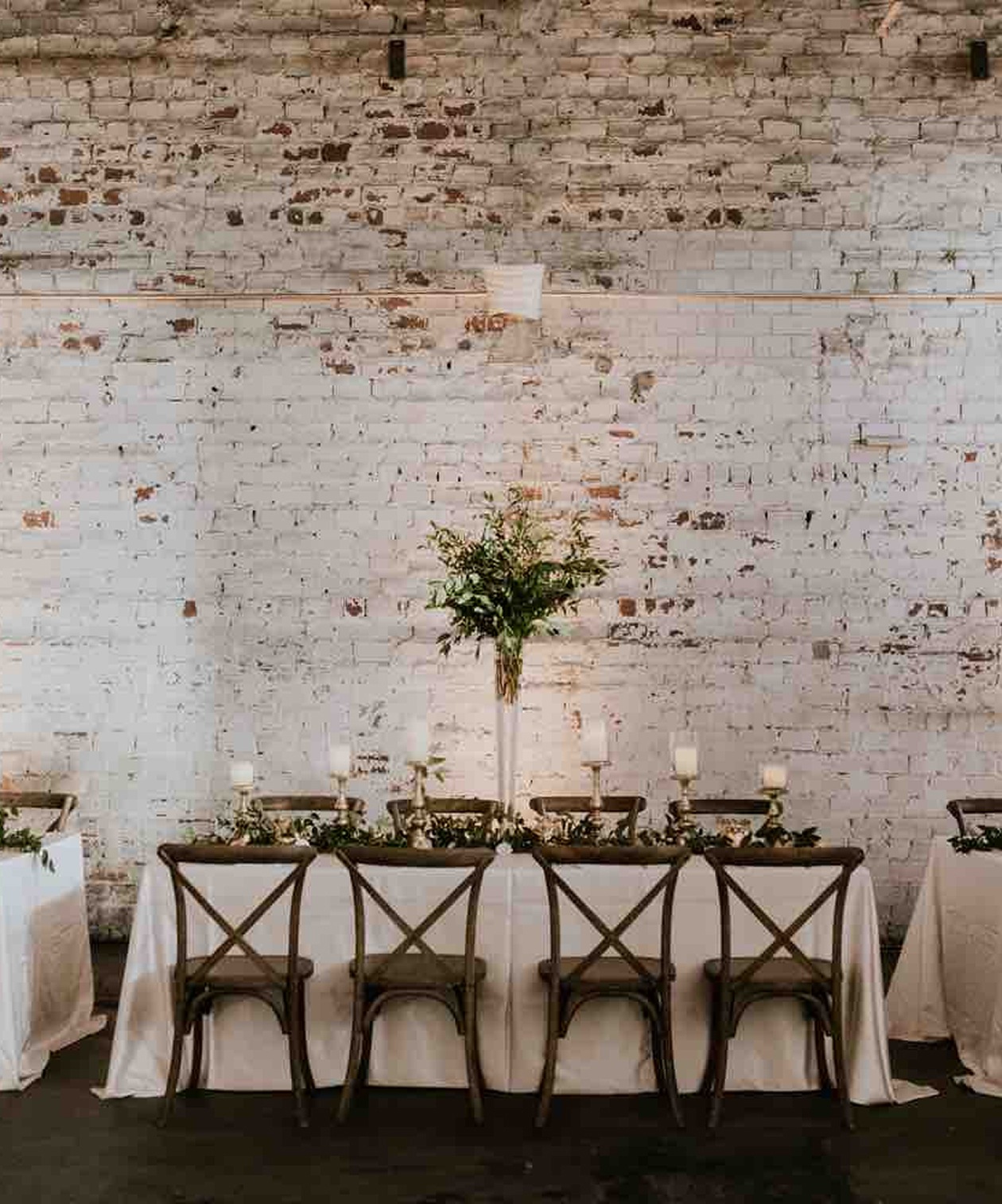 Rustic indoor reception setup with white brick walls, wooden chairs, and greenery decor at Rialto Tampa Theatre